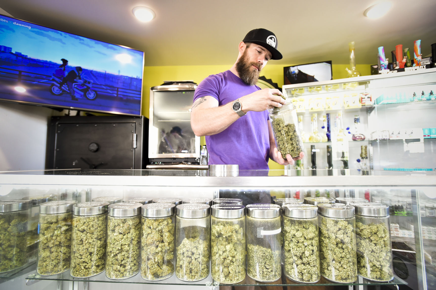 Josh Hughes rifles through a jar of medical marijuana